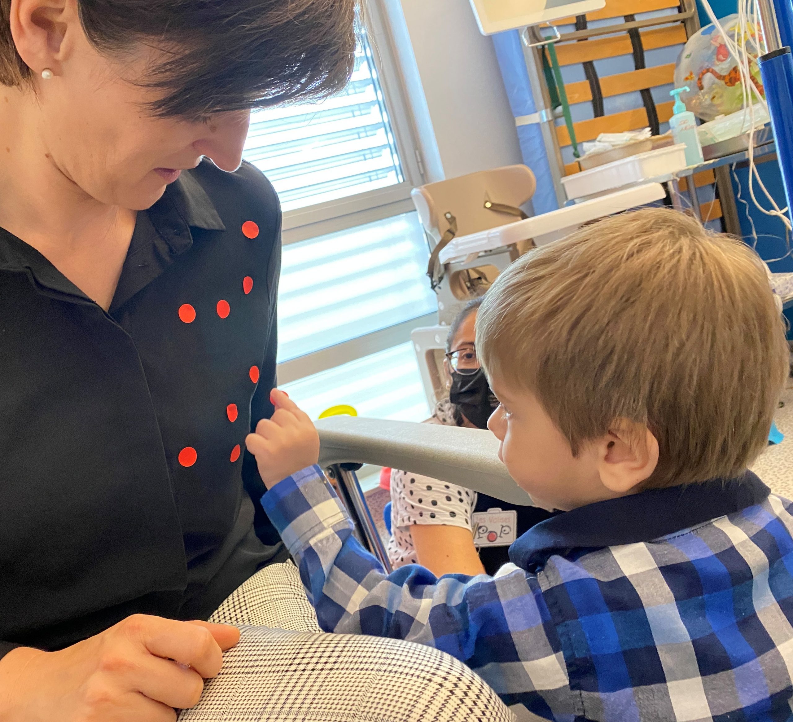 ©Lacompagniepop Un enfant colle des petits autocollants rouges sur la chemine d'une intervenante.